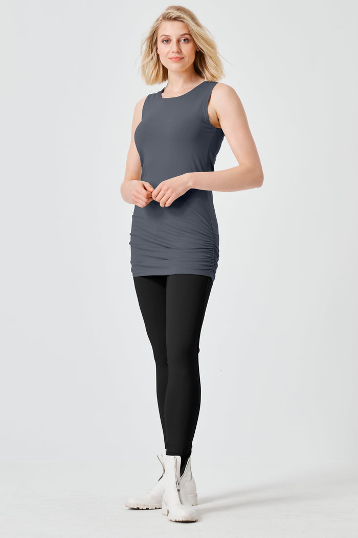 Woman wearing a gray sleeveless lycra top and black leggings on a white background