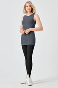 Woman wearing a gray sleeveless lycra top and black leggings on a white background