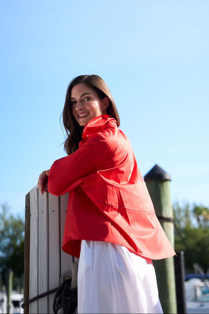 Woman in a red cotton shirt standing by a dock with a clear blue sky.