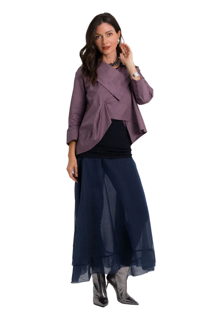 A woman modeling a three-piece outfit consisting of a dusty 100% cotton purple wrap-style jacket, a black ribbed top, and a navy blue sheer midi skirt, paired with dark pointed-toe boots, against a solid light gray background.