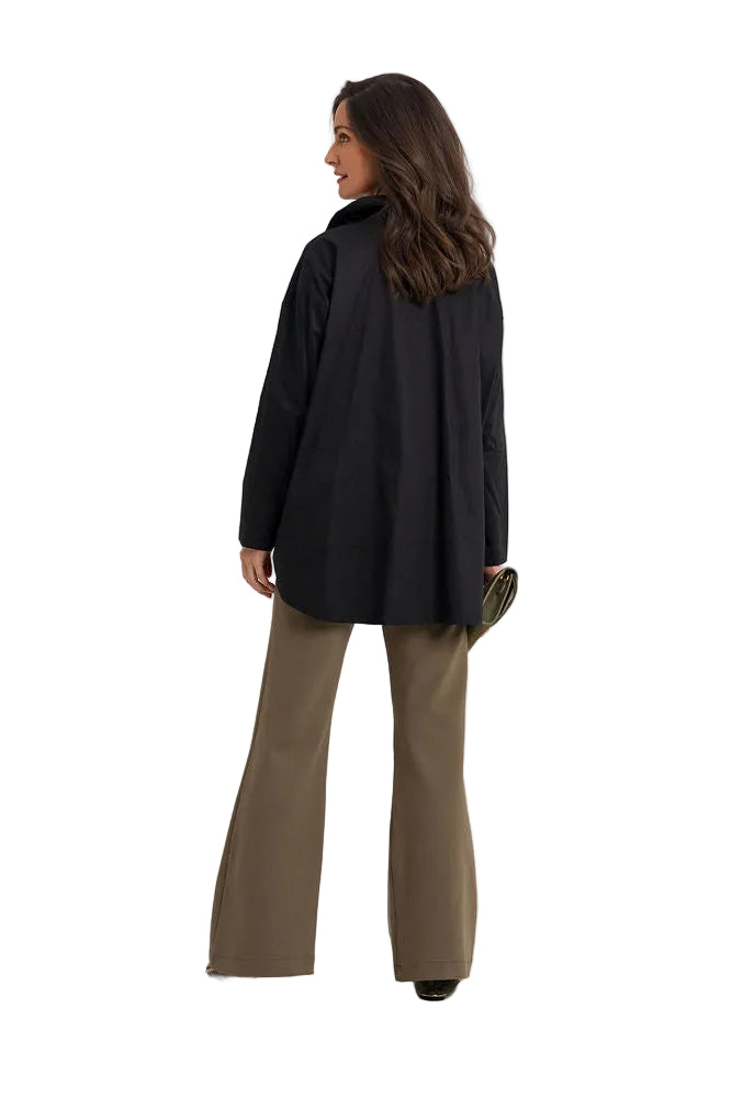 A woman is shown from the back wearing a 100% cotton black oversized long-sleeve jacket and olive green wide-leg trousers, standing against a plain white studio background.
