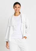 Woman wearing a white french terry outfit with a light jacket on a plain background