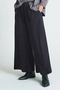 Person wearing black wide-leg pants with a plain background