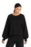 Woman wearing a 100% cotton black oversized sweater against a plain background