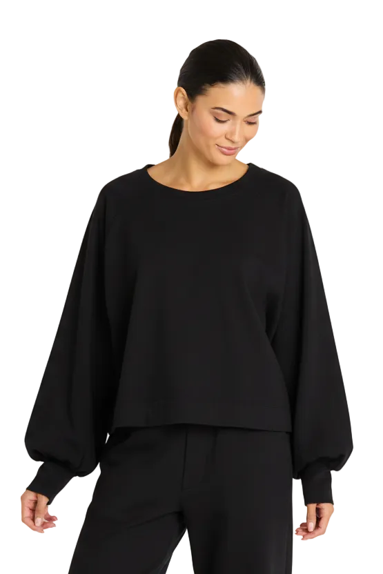 Woman wearing a 100% cotton black oversized sweater against a plain background