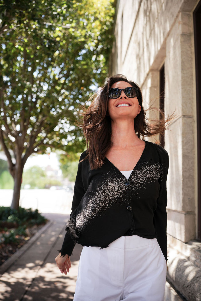 Woman wearing a black cardigan and white shorts and sunglasses outdoors in south florida.