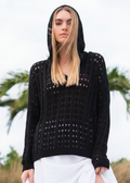 Woman wearing a black crochet sweater against a blurred natural background