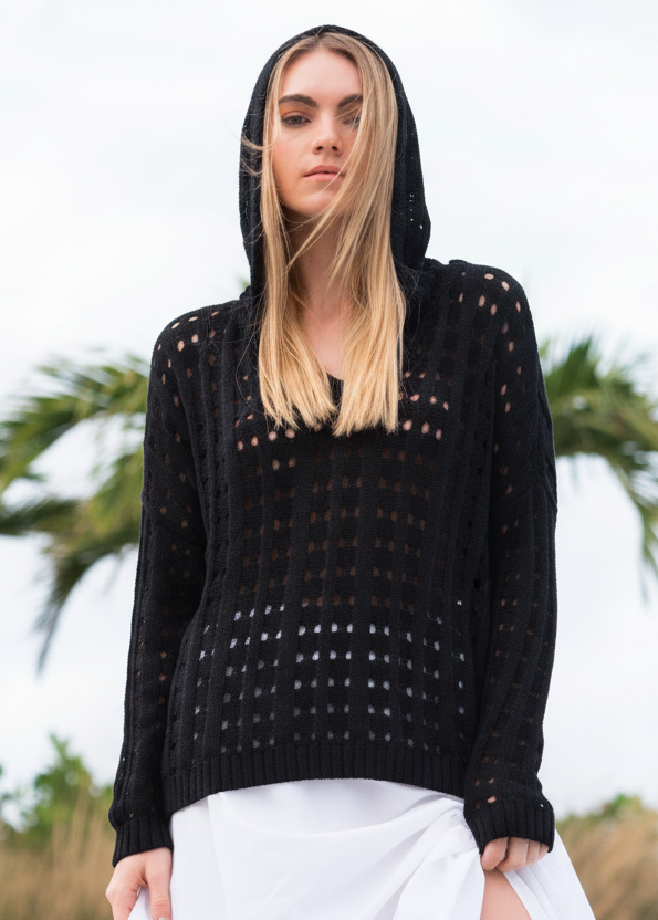 Woman wearing a black crochet sweater against a blurred natural background