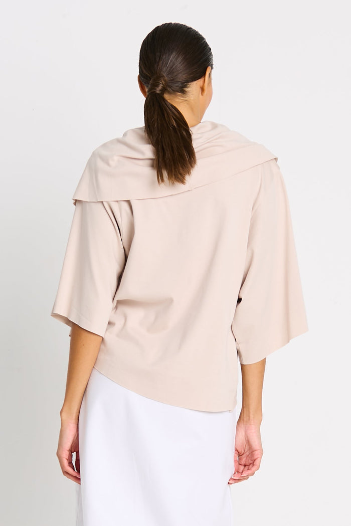 Woman wearing a beige pima cotton top with a plain background