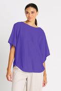 Woman wearing a purple blouse and beige pants on a white background