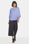Woman wearing a purple pima cotton top and black pants on a white background