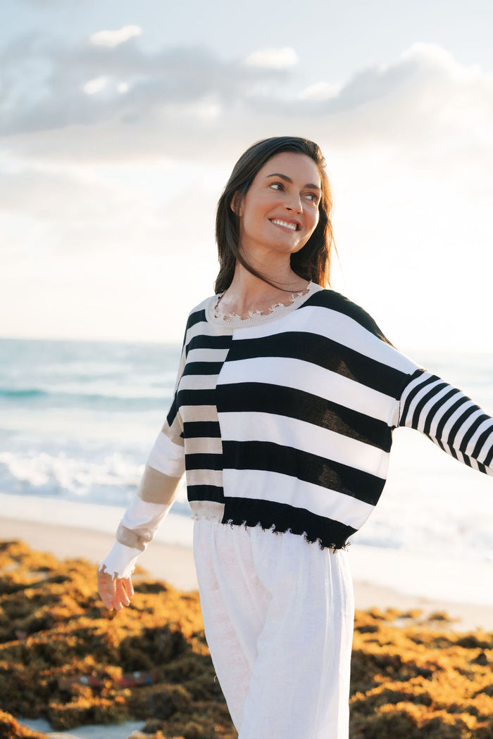 Woman wearing a black and white striped sweater on a beach