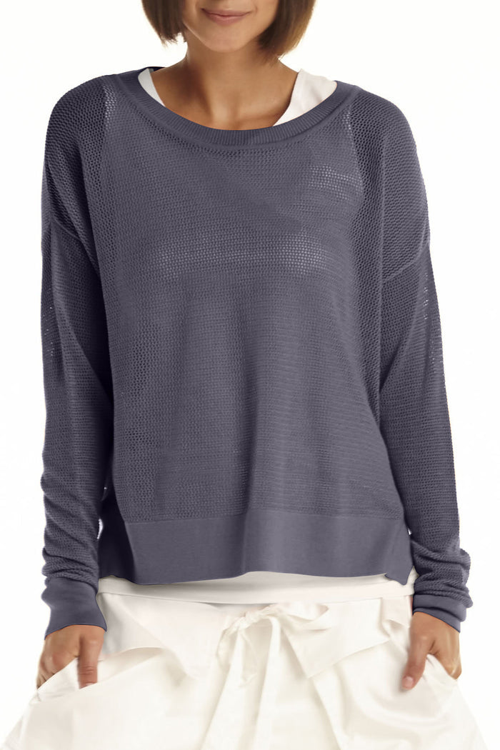 Person wearing a gray textured pima cotton long-sleeve top with white pants on a white background