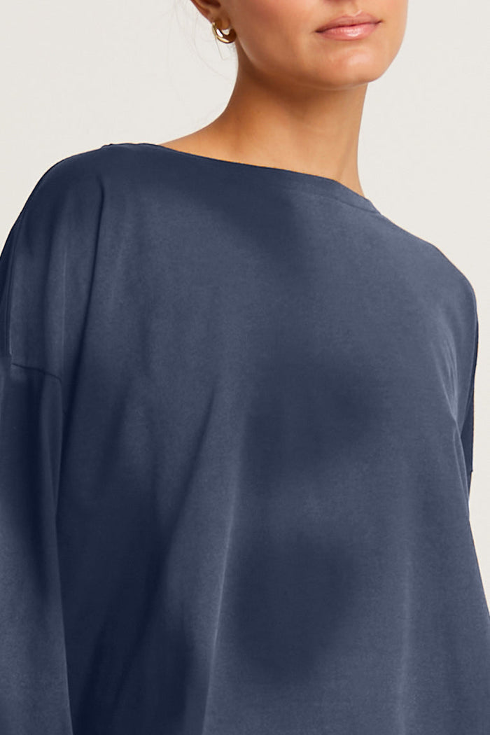 A female model wearing a brown Pima cotton overdyed luxury boxy tee with a relaxed fit, paired with black leggings.
