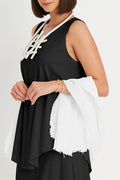 Woman wearing a black sleeveless pima cotton top with white lace details and holding a white scarf.