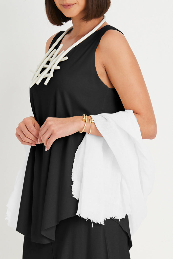 Woman wearing a black sleeveless pima cotton top with white lace details and holding a white scarf.