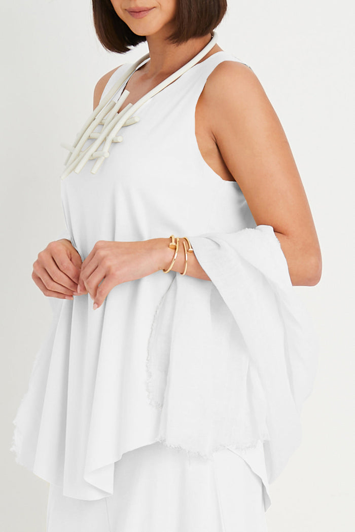 Woman wearing a white sleeveless pima cotton top with a plain background