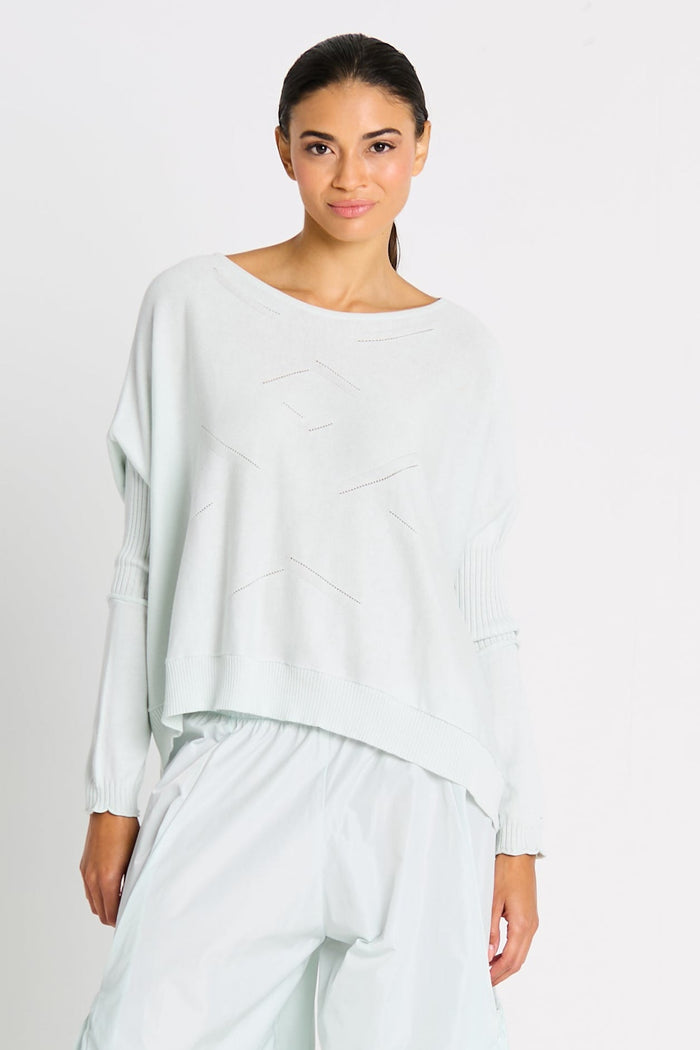 Woman wearing a light mint sweater and pants on a white background