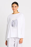 Woman wearing a luxury boxy pima cotton white long-sleeve top with a graphic design on a plain background