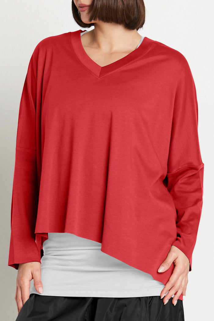Red long-sleeve top worn by a woman on a plain background