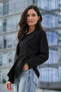 Woman in black scuba blazer and light blue jeans walking in an urban setting with modern buildings in Fort Lauderdale.