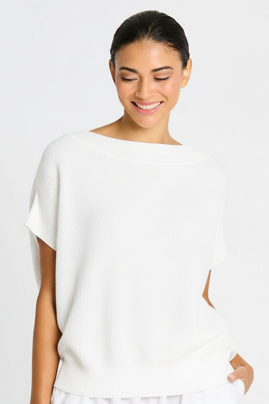 Woman wearing a white pima cotton top against a plain background